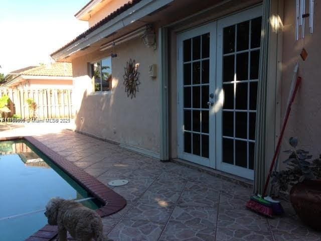 exterior space with a patio, fence, french doors, a fenced in pool, and stucco siding