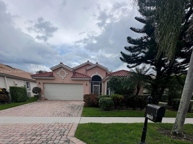 mediterranean / spanish house featuring decorative driveway, a tile roof, an attached garage, and stucco siding