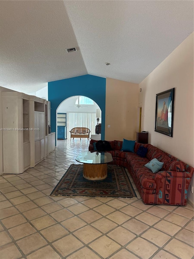 living area featuring lofted ceiling, light tile patterned floors, visible vents, and a textured ceiling