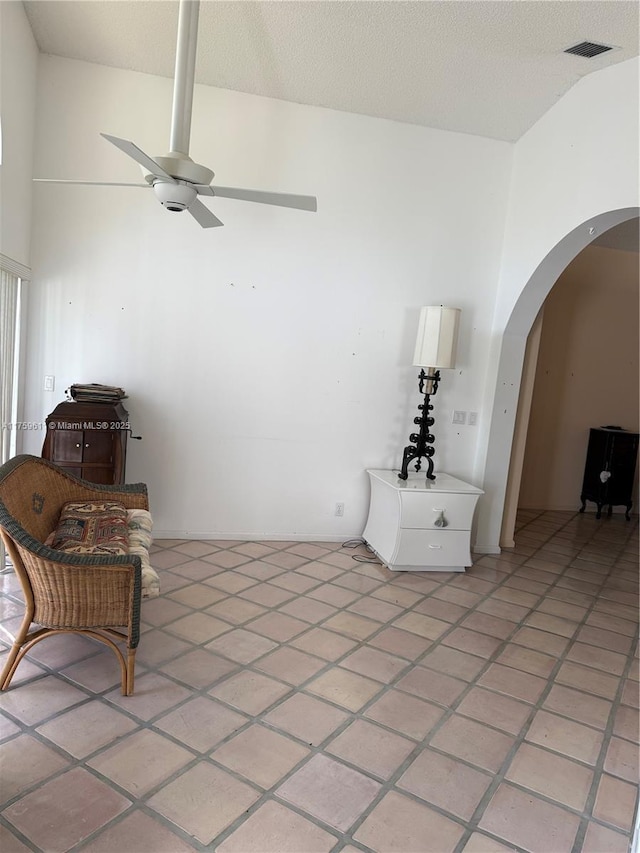 sitting room featuring arched walkways, ceiling fan, a textured ceiling, and high vaulted ceiling