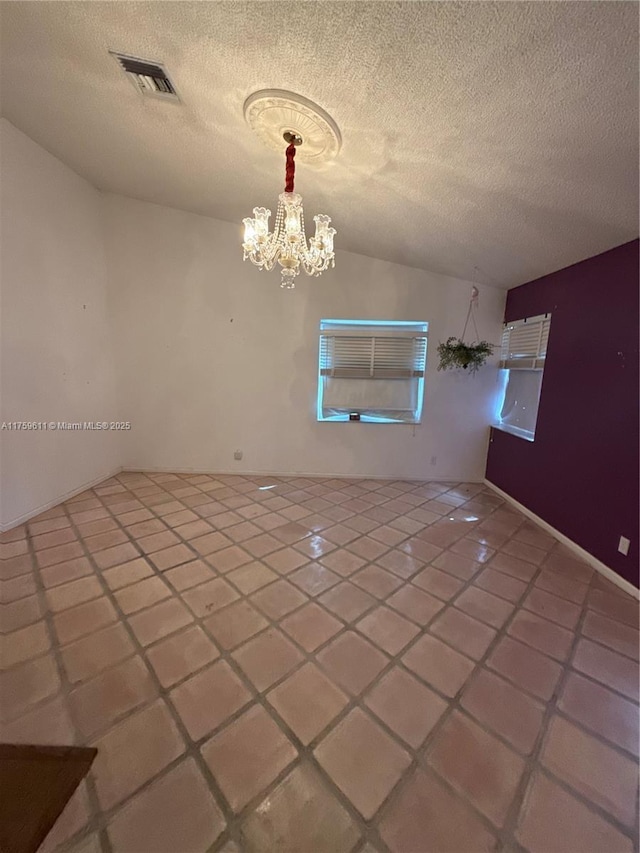 unfurnished room featuring vaulted ceiling, visible vents, a chandelier, and a textured ceiling