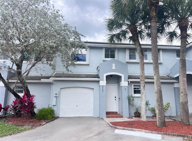 view of property with stucco siding, a garage, and aphalt driveway