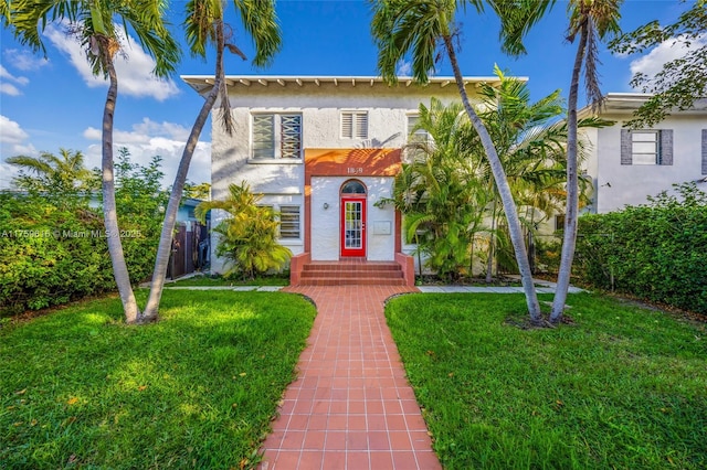 view of front of house featuring fence, a front lawn, and stucco siding