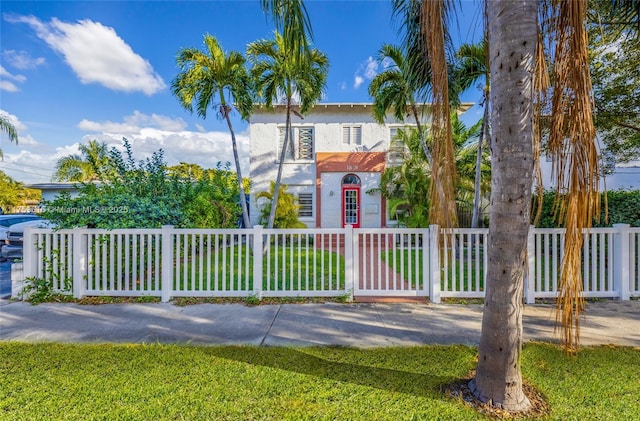 view of front of property with a fenced front yard, a front yard, and stucco siding