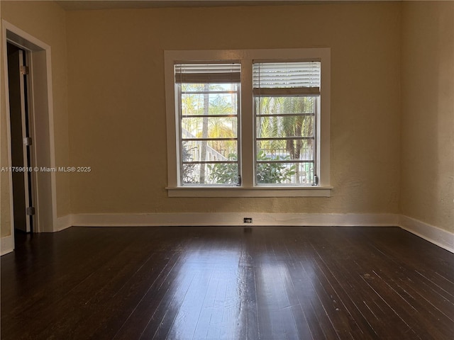 empty room featuring dark wood finished floors and baseboards