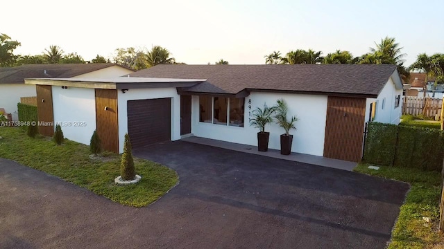 view of front of home featuring fence, a garage, driveway, and stucco siding