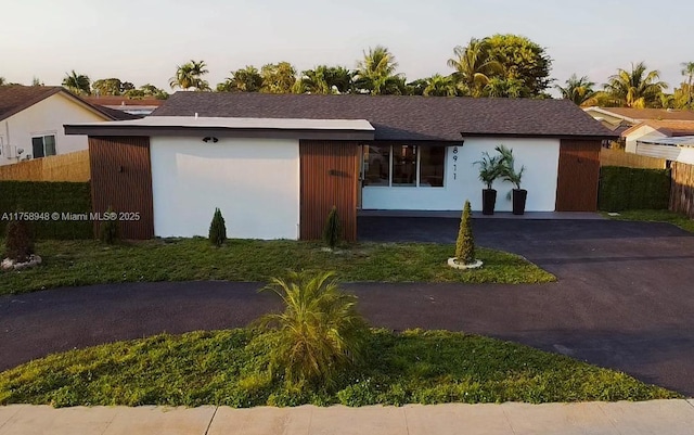 view of front of home with aphalt driveway, stucco siding, and fence