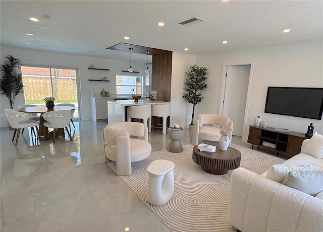 living room with recessed lighting, visible vents, marble finish floor, and a textured ceiling