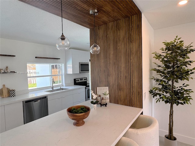 kitchen with modern cabinets, pendant lighting, a sink, appliances with stainless steel finishes, and white cabinets