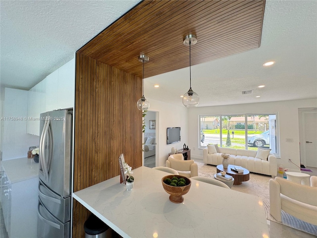 kitchen featuring decorative light fixtures, visible vents, open floor plan, and freestanding refrigerator