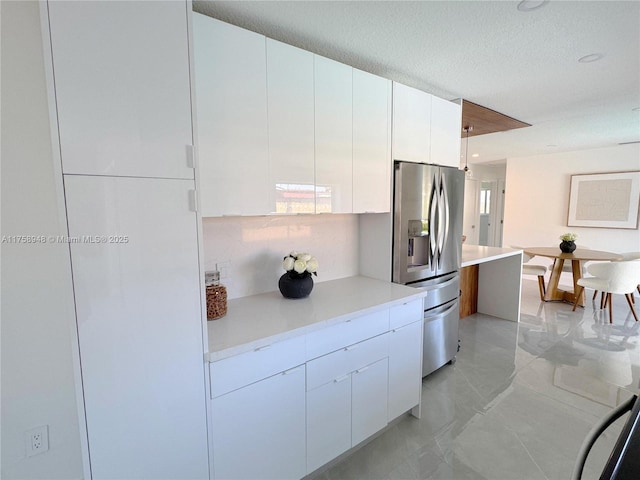 kitchen featuring white cabinetry, modern cabinets, light countertops, and stainless steel refrigerator with ice dispenser