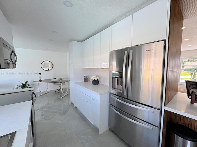 kitchen with light stone counters, stainless steel fridge with ice dispenser, a textured ceiling, white cabinetry, and modern cabinets