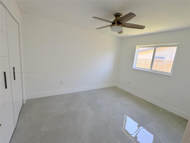 unfurnished bedroom with a ceiling fan and baseboards