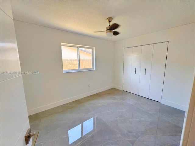 unfurnished bedroom featuring a closet, a textured ceiling, a ceiling fan, and baseboards