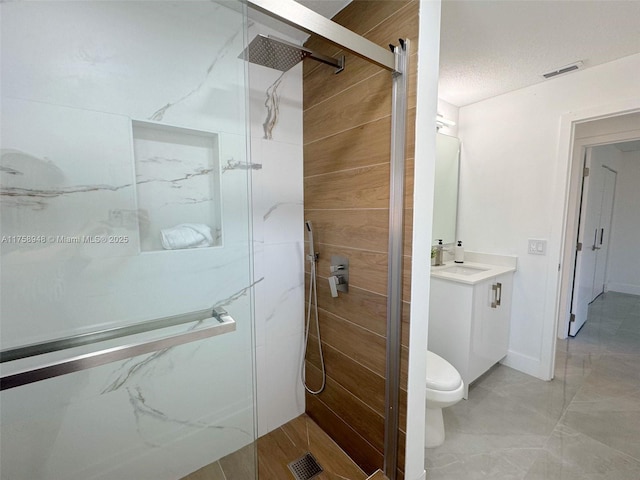 bathroom with visible vents, vanity, a shower stall, and toilet