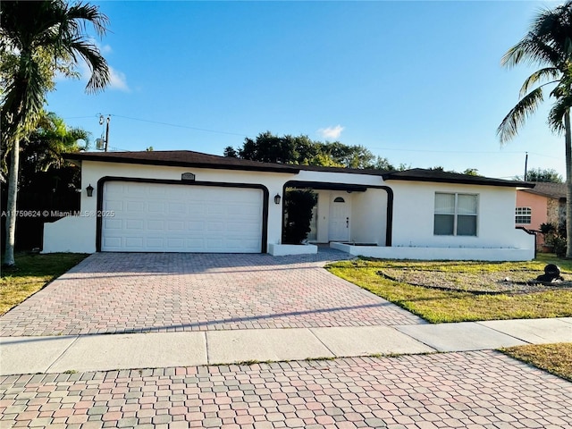 single story home with a garage, a front yard, decorative driveway, and stucco siding