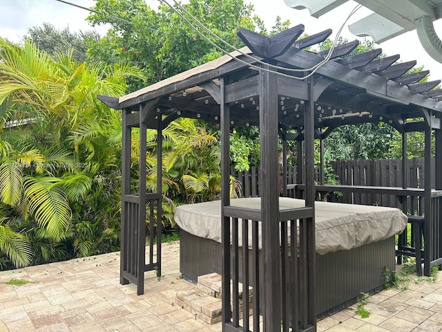 view of patio / terrace featuring a hot tub, fence, and a pergola