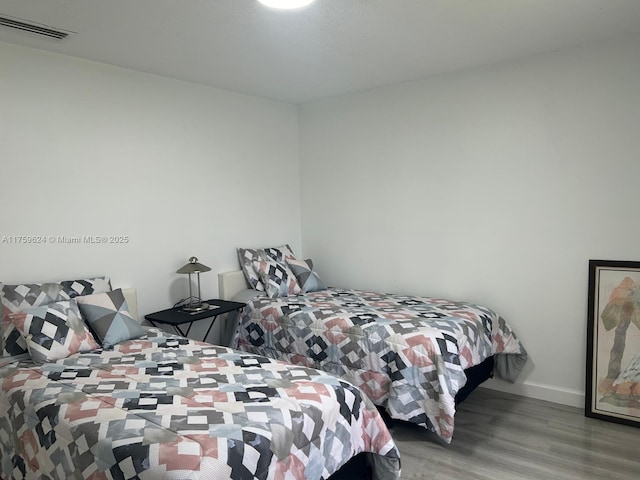 bedroom featuring visible vents, baseboards, and wood finished floors