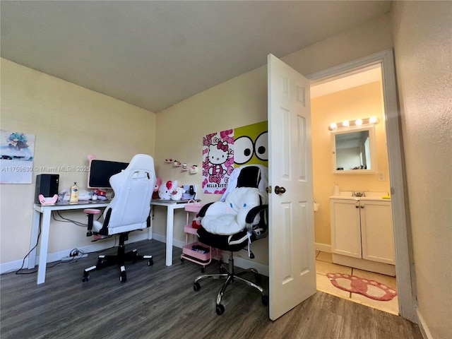 home office with a sink, baseboards, and dark wood finished floors