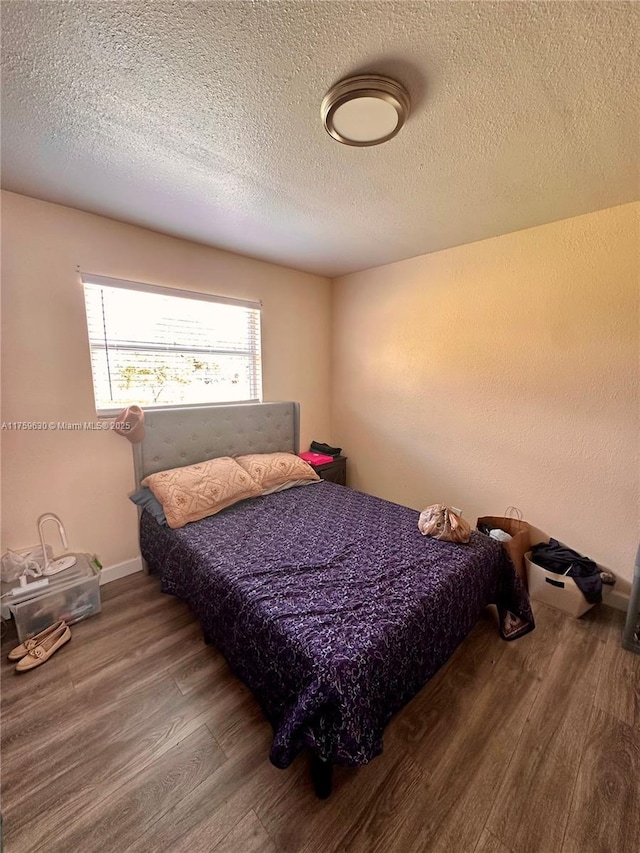 bedroom featuring wood finished floors and a textured ceiling