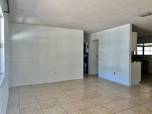 unfurnished room with washer / clothes dryer, visible vents, a textured ceiling, and light tile patterned flooring