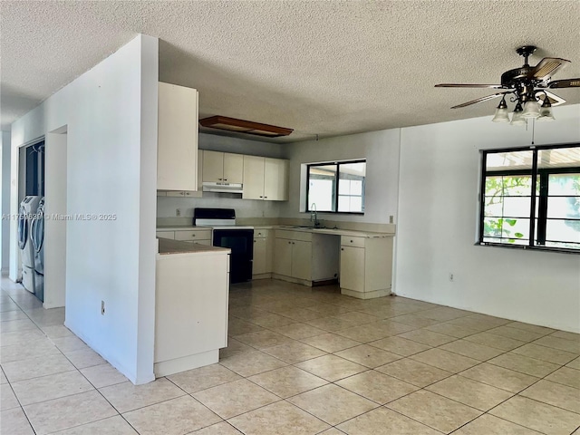 kitchen with light tile patterned floors, under cabinet range hood, a sink, light countertops, and electric range oven