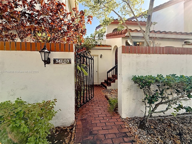 exterior space with a tiled roof, a gate, a fenced front yard, and stucco siding