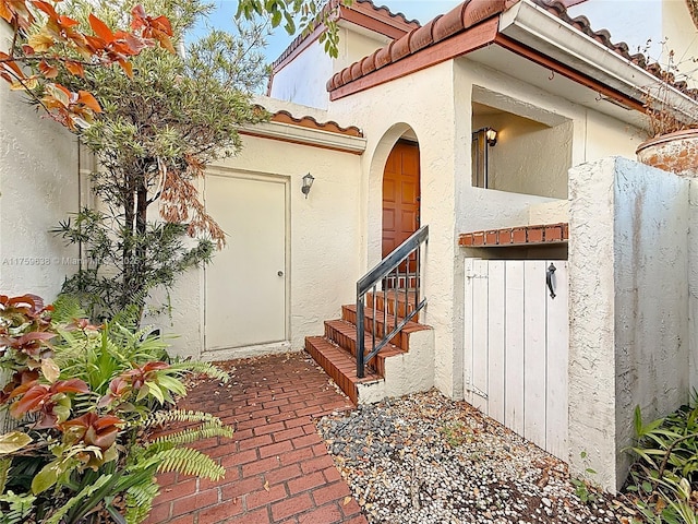 doorway to property featuring a tiled roof and stucco siding