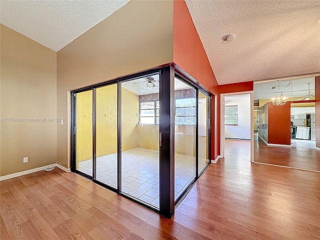 interior space featuring a notable chandelier, a textured ceiling, baseboards, and wood finished floors