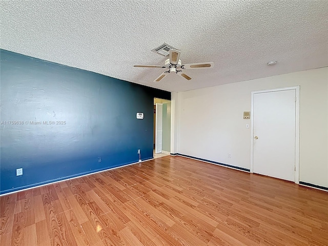 unfurnished room featuring a ceiling fan, visible vents, light wood finished floors, and a textured ceiling