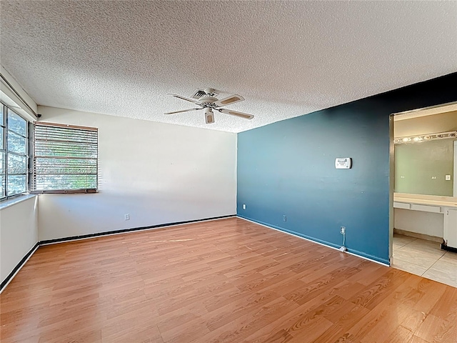 empty room with light wood-type flooring, a textured ceiling, and a ceiling fan