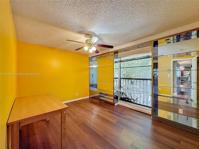 spare room featuring a textured ceiling, a ceiling fan, baseboards, and wood finished floors