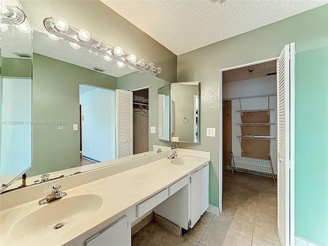 full bathroom featuring a sink, visible vents, a textured ceiling, and tile patterned flooring