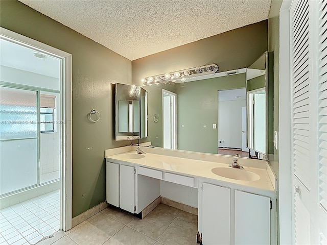 full bathroom with tile patterned floors, double vanity, a textured ceiling, and a sink