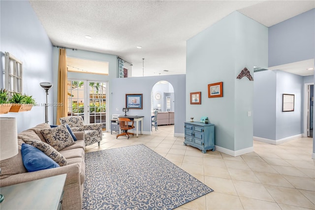 living area featuring arched walkways, light tile patterned floors, high vaulted ceiling, baseboards, and french doors