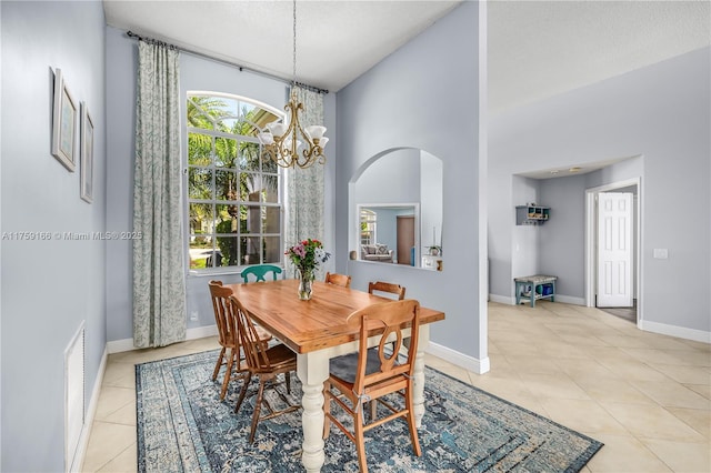 dining space featuring baseboards, arched walkways, a high ceiling, a notable chandelier, and light tile patterned flooring