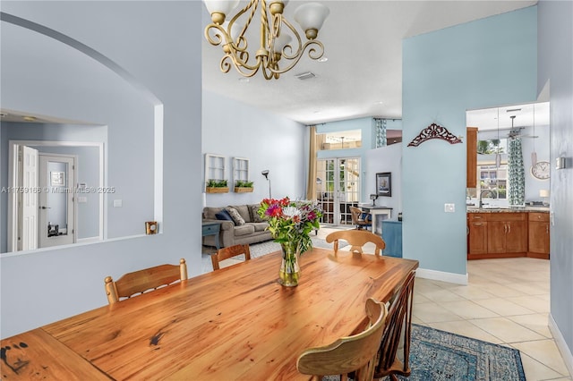 dining room with light tile patterned floors, visible vents, arched walkways, lofted ceiling, and an inviting chandelier