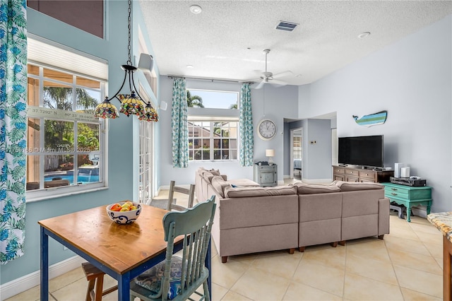 living room featuring light tile patterned floors, visible vents, a ceiling fan, a textured ceiling, and baseboards