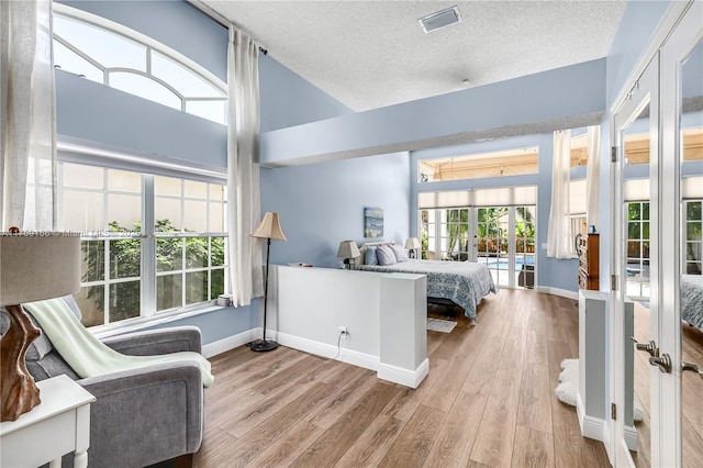 bedroom with visible vents, baseboards, wood finished floors, a textured ceiling, and french doors