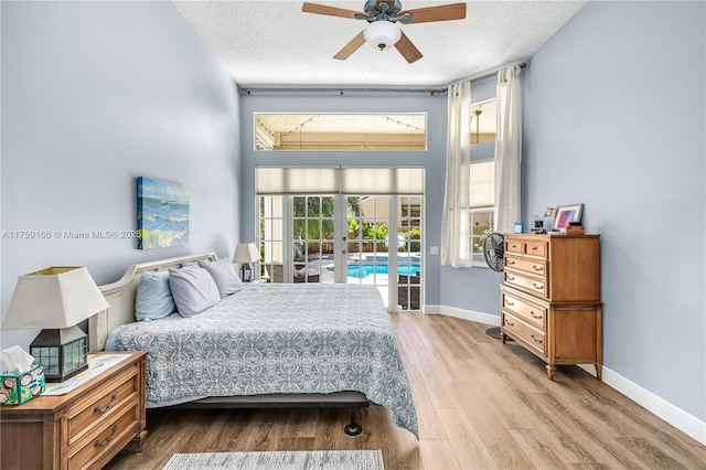 bedroom featuring access to outside, a textured ceiling, baseboards, and wood finished floors