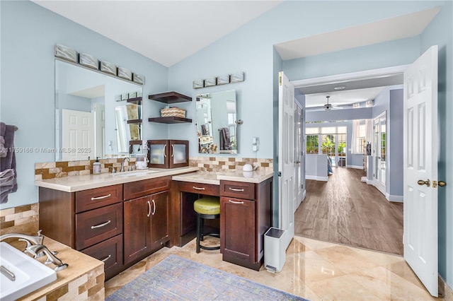 bathroom featuring decorative backsplash, vaulted ceiling, vanity, ceiling fan, and a tub