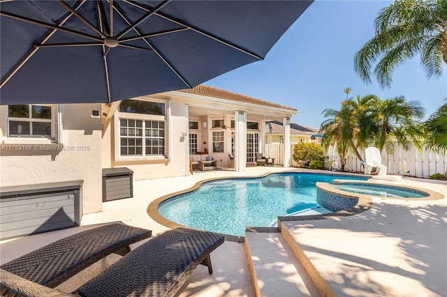 view of pool featuring a pool with connected hot tub, a patio area, and fence