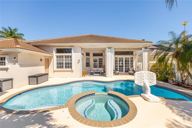 view of pool with a pool with connected hot tub, a patio, and french doors