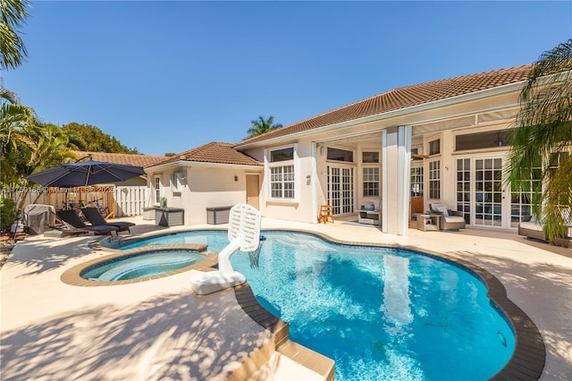 view of swimming pool featuring a pool with connected hot tub, fence, a patio, and french doors