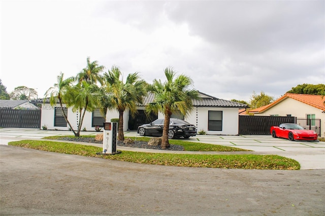 view of front of house featuring a tiled roof, fence, and stucco siding