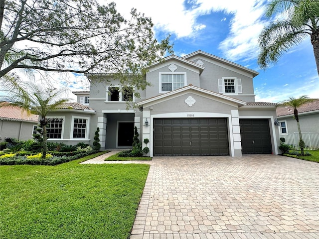 view of front of house with a garage, a tiled roof, decorative driveway, a front lawn, and stucco siding