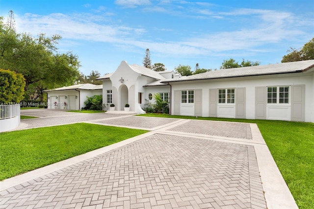 view of front of home featuring a front lawn, decorative driveway, and stucco siding