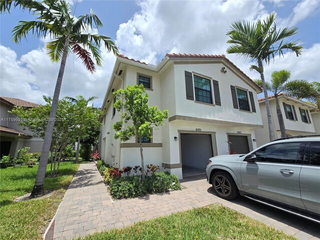 6001 Woods Edge Cir, Riviera Beach, FL 33410 - mediterranean / spanish-style house featuring stucco siding, a tiled roof, an attached garage, and driveway