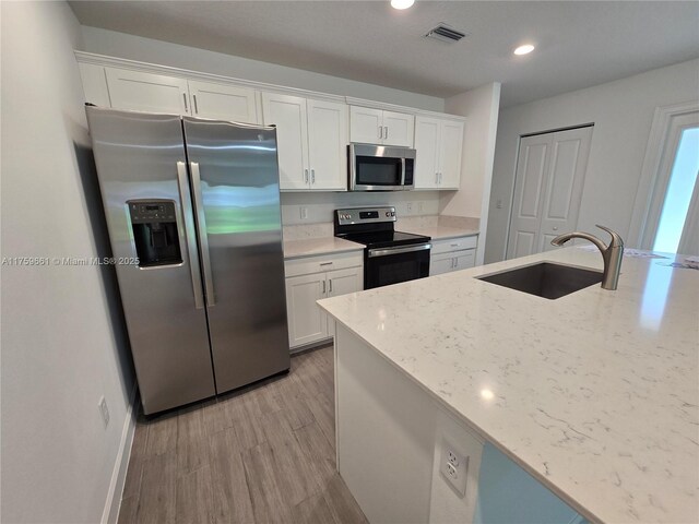 6001 Woods Edge Cir, Riviera Beach, FL 33410 - kitchen with appliances with stainless steel finishes, white cabinetry, light wood-style floors, recessed lighting, and light stone counters