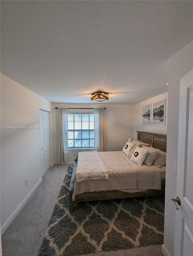 bedroom with carpet flooring, a textured ceiling, and baseboards